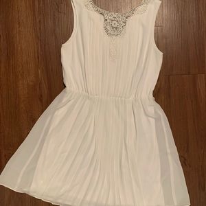 Elegant white pleated dress with front embroidery.